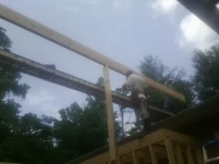 Carpenter setting a ridge beam over a new addition frame — Ice Dam Removal by Roofing Brothers in Appomattox