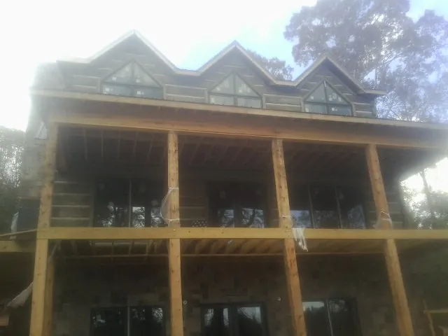 Dormers and porch framing on a large log home under construction — Roof Coating work by our crew in Appomattox