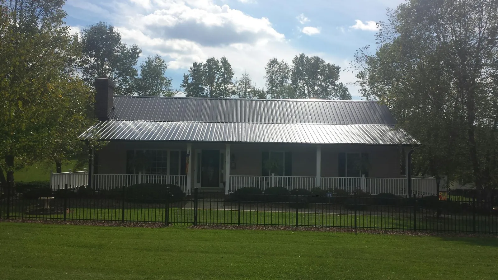 Gray metal roof on a brick ranch with a full width front porch — Gutter Guard Installation work by our crew in Appomattox
