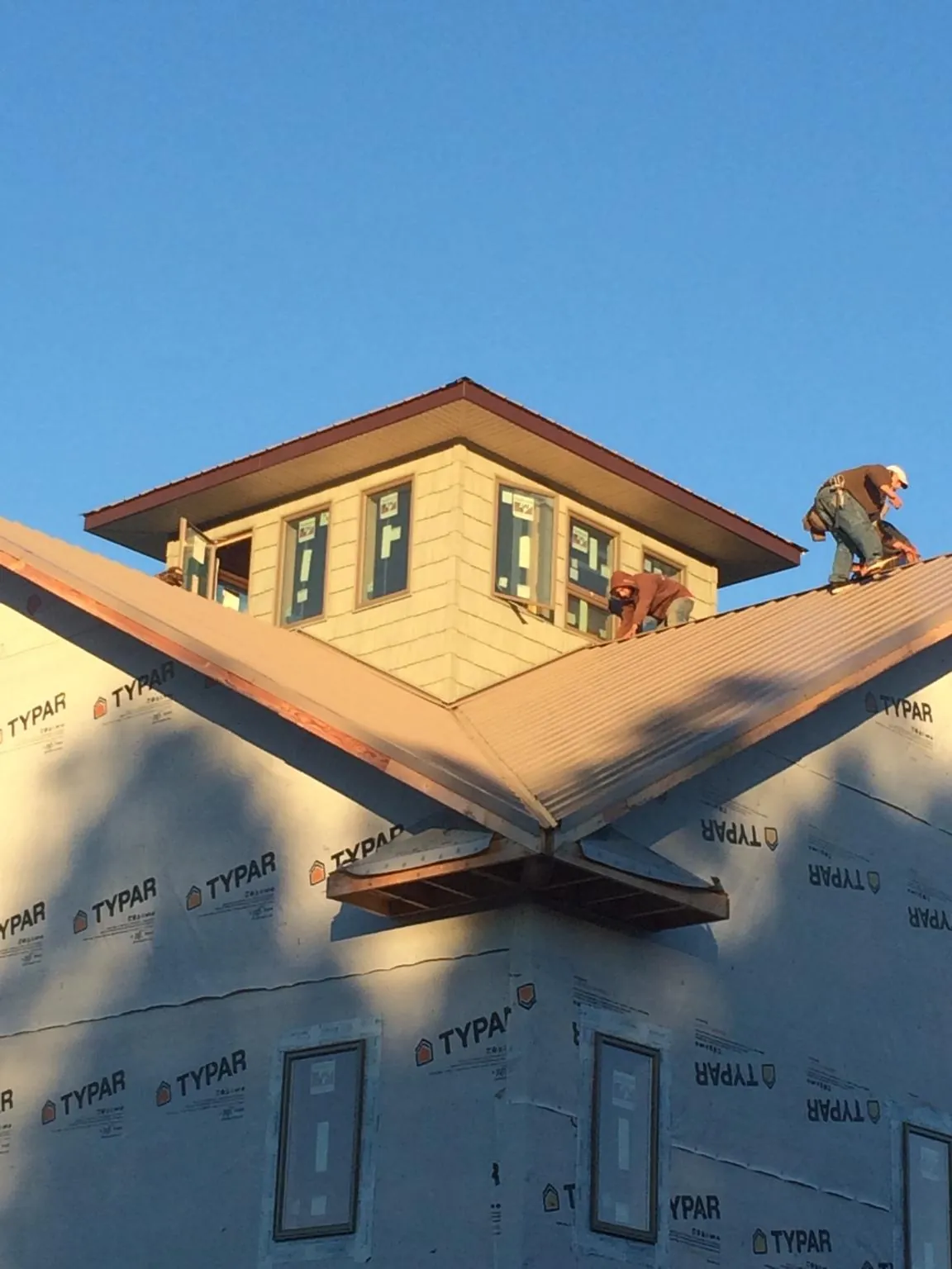 Roofers working around a rooftop cupola on a new metal roof at sunset — Roof Waterproofing in Appomattox by Roofing Brothers